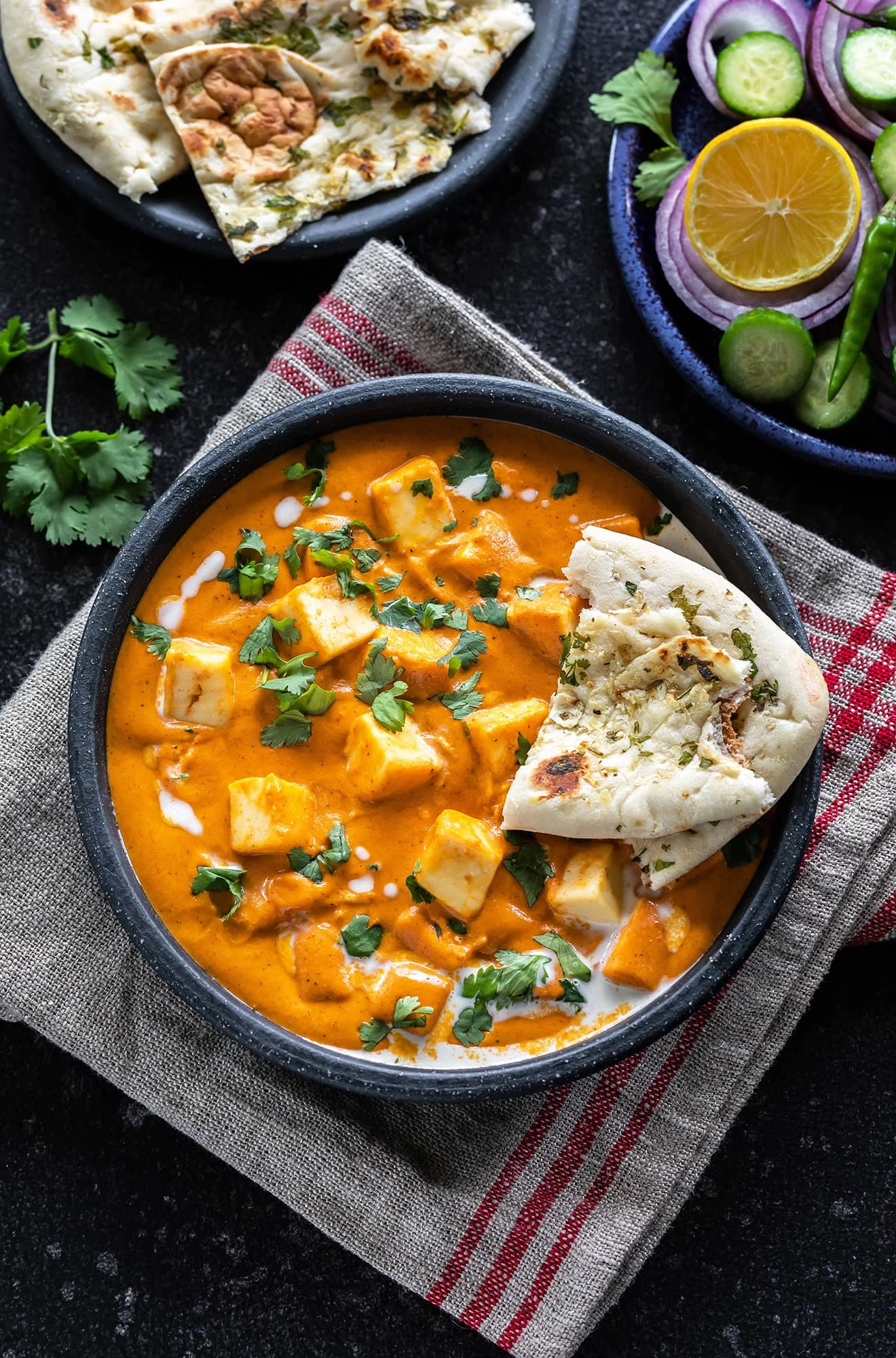 Paneer Butter Masala served with garlic naan, fresh salad, and authentic Indian flavors.