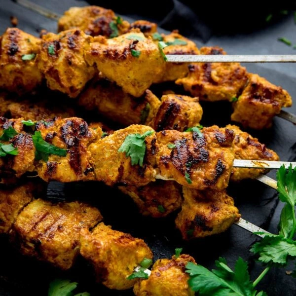Juicy grilled chicken tikka skewers garnished with fresh coriander at Punjabi Zaaika Indian restaurant.