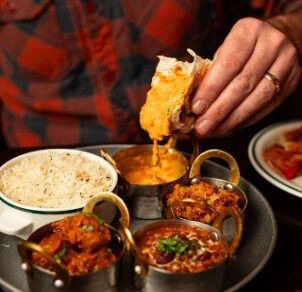 Fresh naan dipped into creamy Indian curry served with basmati rice at Punjabi Zaaika restaurant.