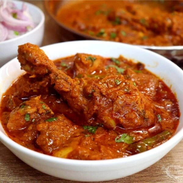 Authentic Punjabi chicken curry with thick spicy gravy served in a white bowl, garnished with fresh coriander.