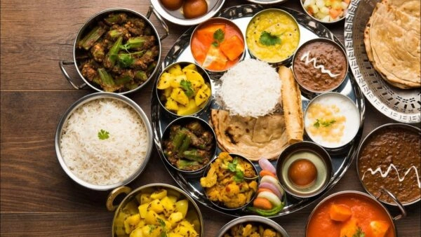Traditional Indian thali with curries, naan, rice, dal, and desserts at an Indian restaurant in Vietnam.